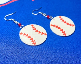 May include: A pair of silver earrings with red beads and white baseball charms. The charms have red stitching.