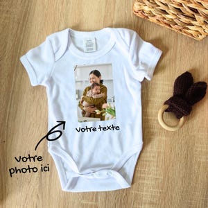 Peut inclure: Un body bébé blanc avec une photo d'une femme tenant un bébé. Le texte "votre texte" est imprimé sous la photo.