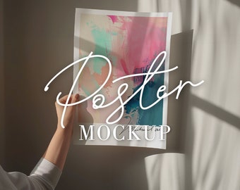 May include: A hand holds up a poster mockup with an abstract painting of pink, blue, and green colors. The text "Poster Mockup" is written in white on the poster.