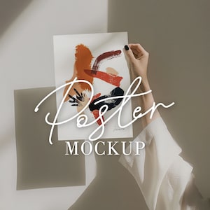 Puede incluir: Una maqueta de póster blanca con una mano sosteniendo el póster. El póster tiene un diseño abstracto con pinceladas negras, naranjas y rojas. El texto "Poster Mockup" está escrito en blanco debajo del diseño.