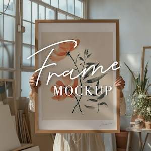 May include: A framed art print featuring a floral watercolor design with orange flowers and green leaves. The frame is made of light-colored wood. The words "Frame Mockup" are written across the image in a cursive font.