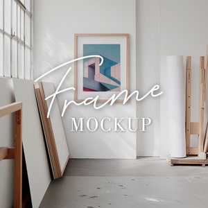 A blank thin oak wood frame mockup, in a minimal bright artist studio, with rolls of art paper and blank canvas