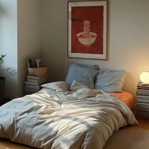 A dark moody bedroom with a floor bed. A large wood oak frame in on the wall above the bed.