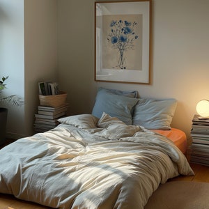 A dark moody bedroom with a floor bed. A large wood oak frame in on the wall above the bed.