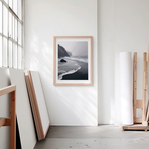 A blank thin oak wood frame mockup, in a minimal bright artist studio, with rolls of art paper and blank canvas