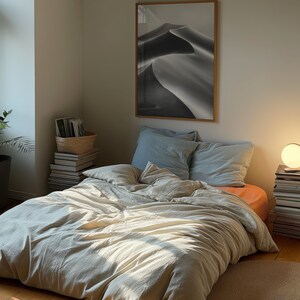 A dark moody bedroom with a floor bed. A large wood oak frame in on the wall above the bed.