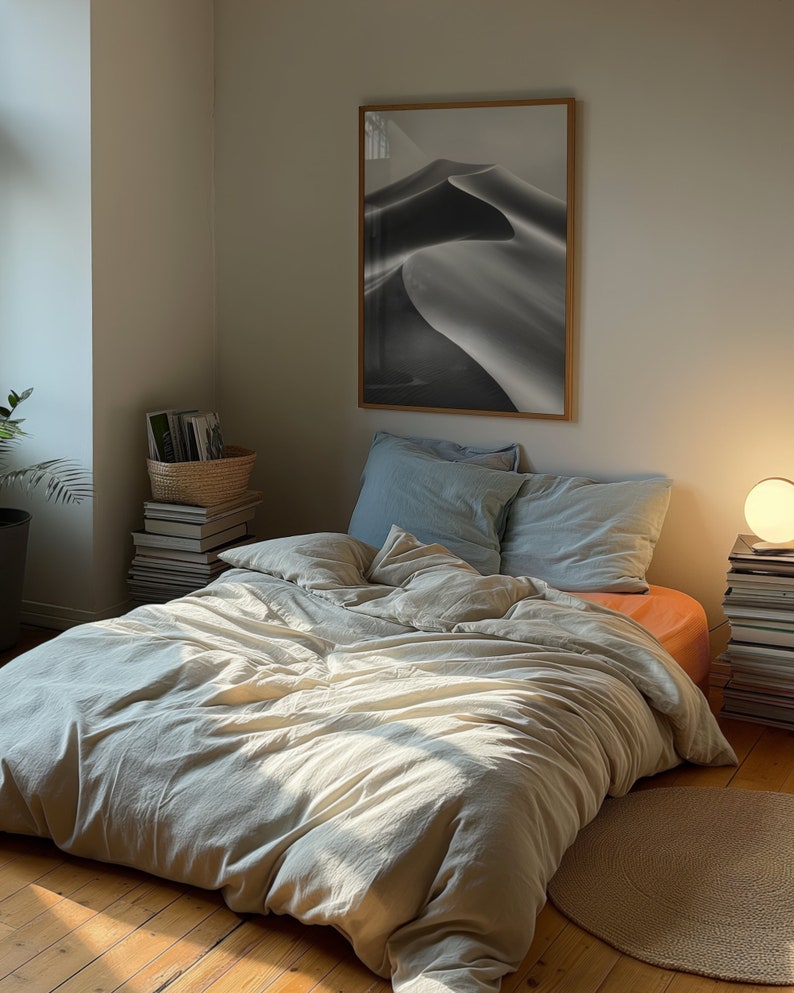A dark moody bedroom with a floor bed. A large wood oak frame in on the wall above the bed.