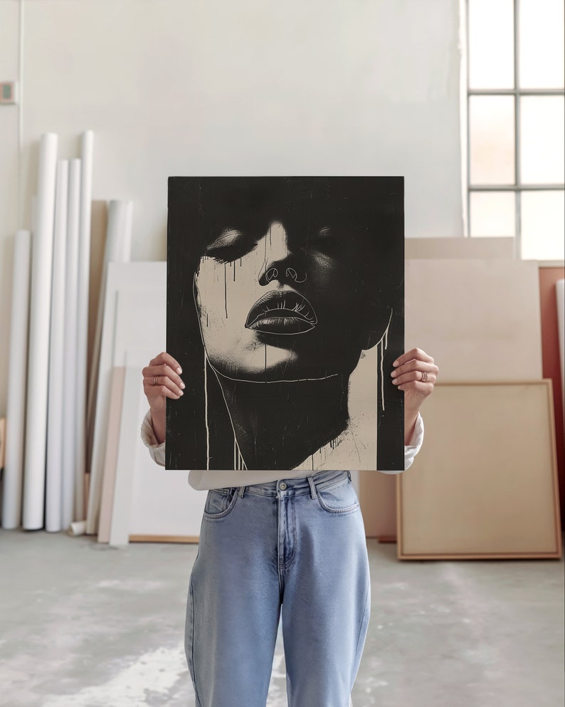 An artist studio room interior. A woman artist holds up a poster in front of her face. Concrete floor. Paper rolls and blank art canvas. Large warehouse windows, sunlight streams in