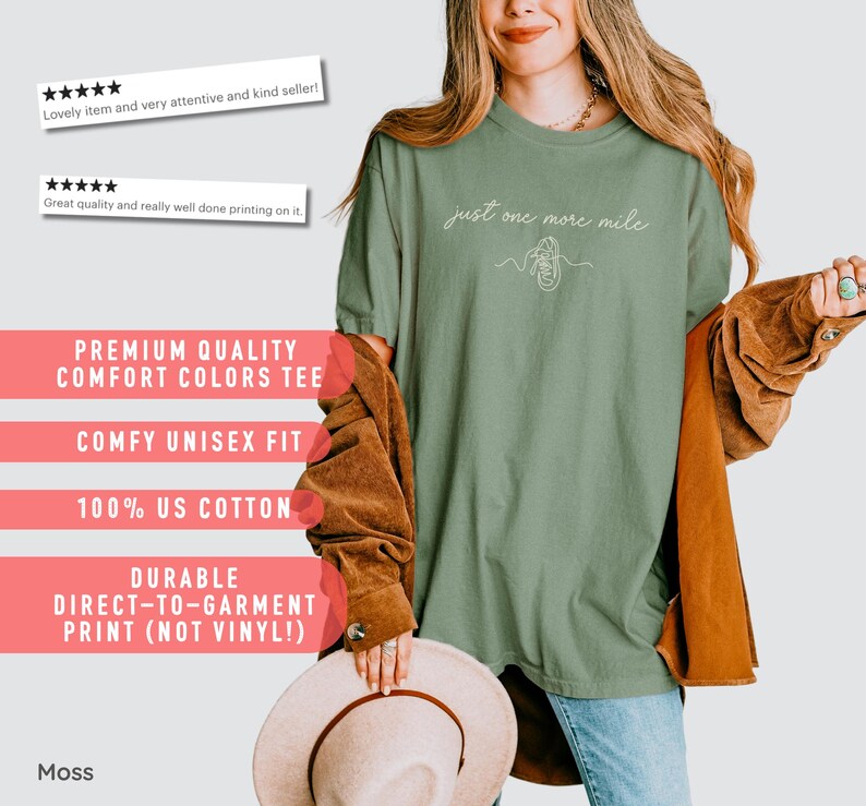 May include: A moss green unisex t-shirt with the text "just one more mile" and a line drawing of a shoe. The shirt is made of 100% US cotton and has a comfy fit. The print is durable and direct-to-garment.