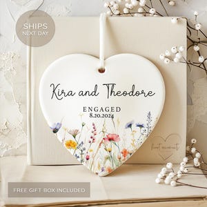 May include: White ceramic heart ornament with a floral design and the text "Kira and Theodore Engaged 8.20.2024".
