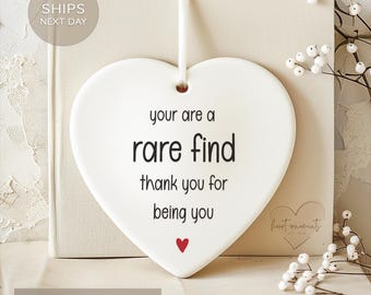 May include: White ceramic heart-shaped ornament with the text "your are a rare find thank you for being you" in black lettering. A small red heart is at the bottom of the ornament.