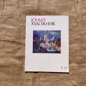 Op de afbeelding: Een vintage tijdschriftcover met een schilderij van een havenscène met boten en een stadsbeeld op de achtergrond. Het tijdschrift is getiteld "Юный художник" (Jonge kunstenaar) en het nummer is 8, 1983.