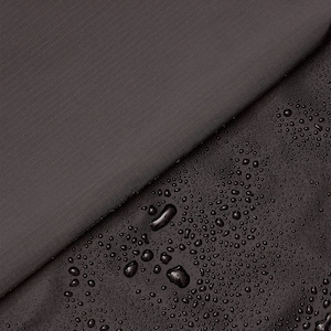May include: Close-up of a dark gray fabric with water droplets on the surface. The fabric is smooth and has a subtle texture. The water droplets are clear and round.