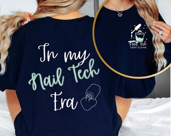 Op de afbeelding: Een donkerblauw T-shirt met de tekst "In my Nail Tech Era" en een afbeelding van een nagellak flesje. De achterkant van het shirt heeft een klein logo met de tekst "Nail Tech Sara Elaine" en een afbeelding van een nagellak flesje.