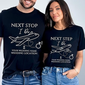 May include: Black t-shirts with white graphic text and illustrations. The text reads "NEXT STOP I Do" with an airplane, ring, and other wedding-themed graphics. The bottom text says "YOUR WEDDING NAME WEDDING LOCATION".