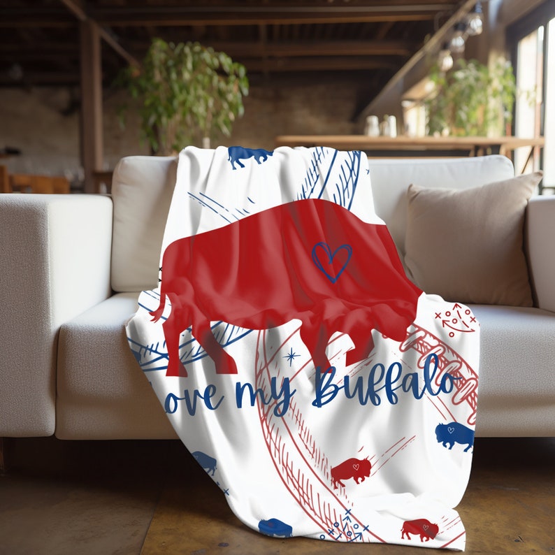 Peut inclure: Une couverture blanche avec une silhouette de buffle rouge, des c&oelig;urs bleus et rouges et le texte "Love my Buffalo". La couverture a un motif bleu et rouge avec un ballon de football et d'autres images li&eacute;es au sport.