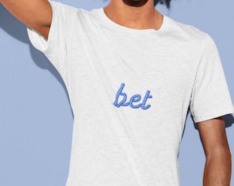 May include: A white t-shirt with a blue embroidered word "bet" on the front.