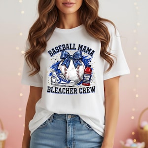 Puede incluir: Camiseta blanca con un diseño de béisbol. El diseño incluye una pelota de béisbol con un lazo azul, una zapatilla alta azul y una botella de bebida deportiva roja. El texto dice "BASEBALL MAMA BLEACHER CREW."