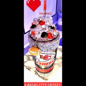 K&ouml;nnte beinhalten: Ein durchsichtiger, glitzernder Becher mit einem rot-wei&szlig;-schwarzen Kansas City Chiefs Logo. Der Becher hat einen rot-schwarzen Strohhalm und einen Fu&szlig;ball-Anh&auml;nger. Der Text "5oz Rocks" ist auf dem Becher sichtbar.