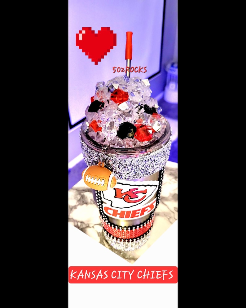 K&ouml;nnte beinhalten: Ein durchsichtiger, glitzernder Becher mit einem rot-wei&szlig;-schwarzen Kansas City Chiefs Logo. Der Becher hat einen rot-schwarzen Strohhalm und einen Fu&szlig;ball-Anh&auml;nger. Der Text "5oz Rocks" ist auf dem Becher sichtbar.