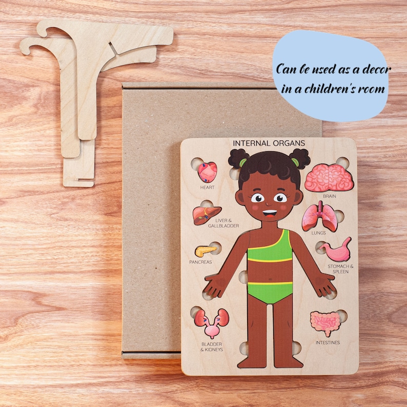 Op de afbeelding: Houten puzzel met het lichaam van een kind met gelabelde interne organen. De puzzel bevat hart, hersenen, longen en andere organen. De tekst "INTERNAL ORGANS" staat bovenaan. De tekst "Can be used as a decor in a children's room" is ook aanwezig.