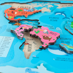 Könnte beinhalten: Ein hölzernes Weltkarten-Puzzle mit farbenfrohen Kontinentteilen. Der nordamerikanische Bereich ist orange, während südamerikanische Länder wie Brasilien rosa sind. Die blaue Meeresbasis zeigt Illustrationen von Meereslebewesen und Ländernamen.