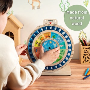 May include: A wooden perpetual calendar with a circular design, featuring months, days, and moon phases. The calendar is made from natural wood and includes colorful illustrations for each month. The text "TODAY IS" is visible at the top.