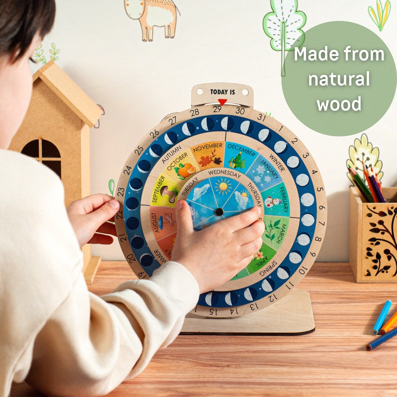May include: A wooden perpetual calendar with a circular design, featuring months, days, and moon phases. The calendar is made from natural wood and includes colorful illustrations for each month. The text "TODAY IS" is visible at the top.