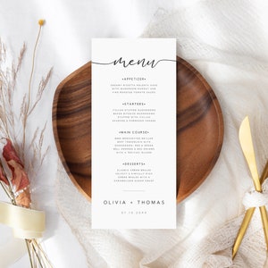 May include: A wedding menu card with a simple, elegant design. The card is white with black text and features a handwritten "Menu" title. The menu includes starters, main course, and desserts. The bottom of the card features the names "Olivia + Thomas" and the date "07.10.20XX".