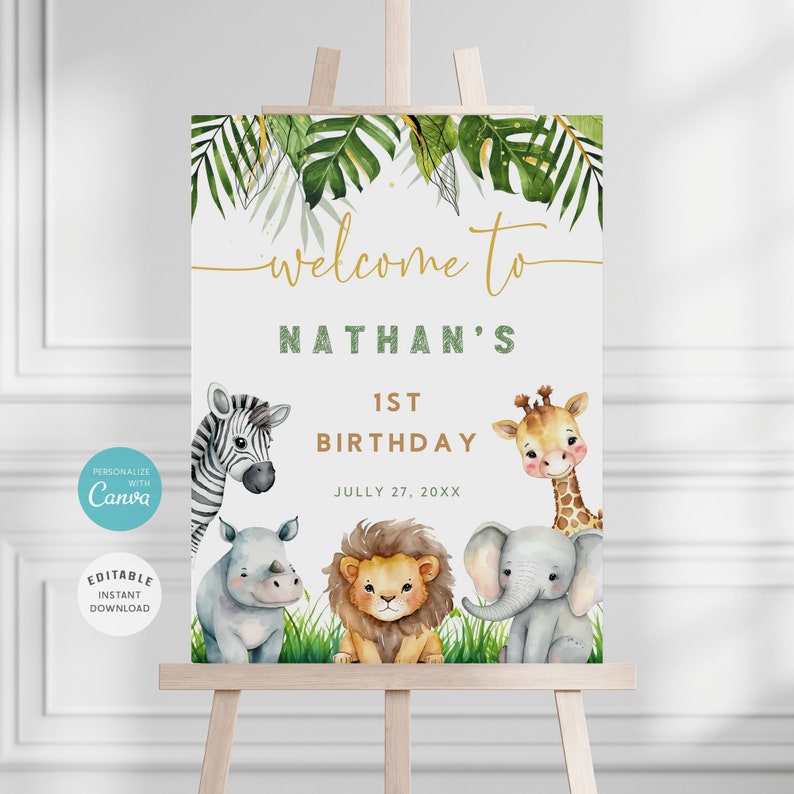 May include: Welcome to Nathan's 1st Birthday sign with a jungle theme. The sign features a zebra, giraffe, rhino, lion, and elephant with green leaves and gold glitter accents. The date is July 27, 20XX.