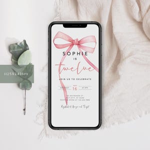 May include: A pink watercolor bow with a white background and the text "Sophie is twelve" on a smartphone screen. The text below the bow reads "Join us to celebrate" and includes the date and time of the event. The text at the bottom of the screen reads "Registered at Amazon and Target".