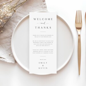 May include: A white card with the text "Welcome and Thanks" printed in black. The card also includes a message thanking guests for sharing in the joy of the wedding day and a message from the couple, Emily & Kevin.