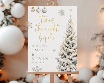 May include: A cream-colored sign on a wooden easel with the text "Twas the night before" in gold script. The sign features a watercolor illustration of a snowy Christmas tree and snowflakes, with the names "Emil & Kevin" below.
