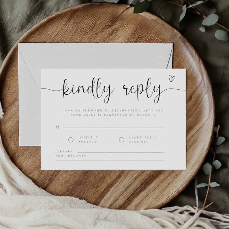 May include: A white RSVP card with black text that reads "kindly reply". The card has a small heart symbol and a section for guests to indicate whether they will be able to attend the event. The card also includes a section for dietary requirements.
