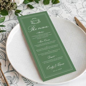 May include: A rectangular sage green menu card with white text and a double-line border. The header reads The menu, followed by sections for Starter, Main Course, and Dessert. It includes the names Emily & Lennox and the date 08.14.20XX.