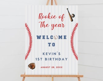 May include: A white and blue baseball-themed welcome sign with red stitching. The sign reads "Rookie of the year, Welcome to Kevin's 1st Birthday, August 28, 20XX".