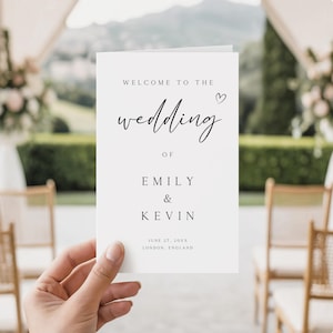 Może przedstawiać: Biały program ślubny z czarnym pismem. Tekst brzmi „Witamy na ślubie Emily i Kevina” z datą i miejscem na dole. Program jest trzymany przed rozmytą sceną ślubną na świeżym powietrzu.
