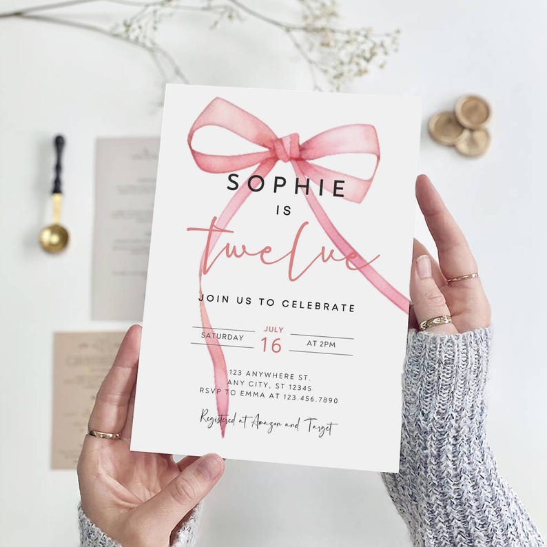K&ouml;nnte beinhalten: Ein rosa Aquarell-Schleife mit dem Text "Sophie ist zw&ouml;lf" auf wei&szlig;em Hintergrund. Die Einladung enth&auml;lt Details f&uuml;r eine Geburtstagsfeier am 16. Juli um 14:00 Uhr. Die Adresse und RSVP-Informationen sind ebenfalls enthalten. Die Einladung gibt an, dass die Veranstaltung bei Amazon und Target registriert ist.