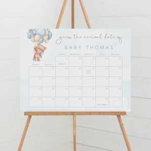 Può includere: Un calendario blu e bianco con un orsacchiotto che tiene dei palloncini. Il calendario è per indovinare la data di arrivo di Baby Thomas. La data presunta è il 10 agosto.