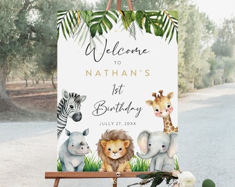 May include: Welcome to Nathan's 1st Birthday sign with a jungle theme. The sign features a white background with green tropical leaves and gold glitter. There are five watercolor animal illustrations: a zebra, a rhinoceros, a lion, a giraffe, and an elephant.