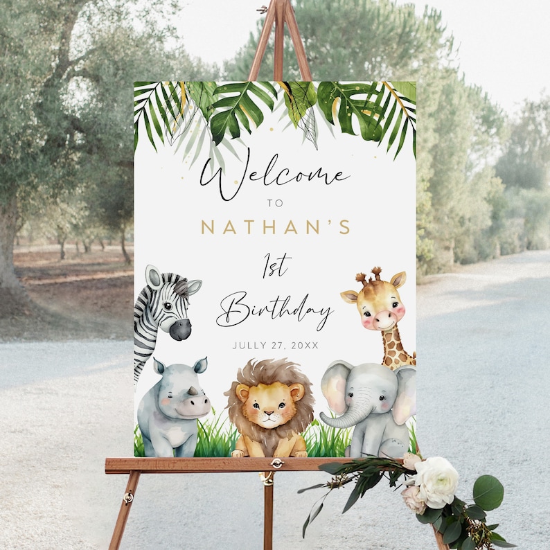 Op de afbeelding: Welkom bij Nathans 1e verjaardagsschild met jungle thema. Het bord heeft een witte achtergrond met groene tropische bladeren en gouden glitter. Er zijn vijf aquarel dierillustraties: een zebra, een neushoorn, een leeuw, een giraffe en een olifant.