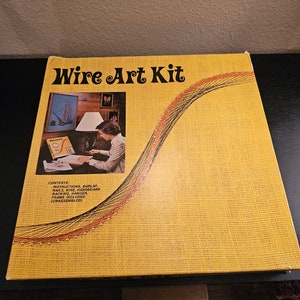 May include: A yellow box with the words "Wire Art Kit" printed in black. The box shows a woman working on a wire art project. The box includes instructions, burlap, nails, wire, hardboard backing, a hanger, and a frame.