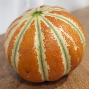 May include: A round, orange and green melon with a striped pattern.