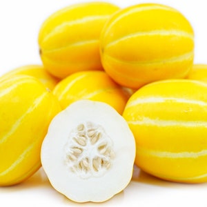 May include: A group of yellow melon fruits with a striped pattern. One melon is cut in half, revealing white flesh and seeds.