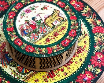 May include: A round wooden puzzle with a vibrant floral design in red, yellow, and green. The puzzle features a central illustration of a horse-drawn carriage with figures and text around the border. The puzzle is on a wooden surface.