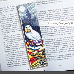May include: A white owl with a letter in its beak perched on a stack of books. The owl is in front of a dark blue background with a castle in the distance. The bookmark is made of cross-stitch.