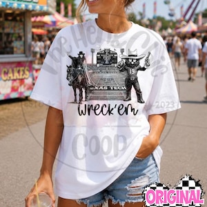 Könnte beinhalten: Ein weißes kurzärmeliges T-Shirt mit einem Grafikdruck eines Cowboys auf einem Pferd und einem Maskottchen mit Cowboyhut, das einen Football auf einem Spielfeld hält. Der Text "Texas Tech" und "Wreck'em" ist in Schwarz auf das Shirt gedruckt.