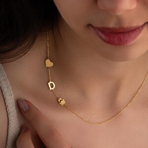 May include: A gold necklace with a heart, letter D, and paw print charm.