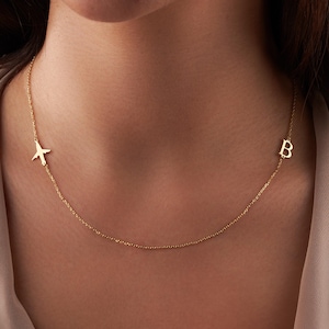 May include: A gold necklace with a small airplane charm and a letter 'B' charm.