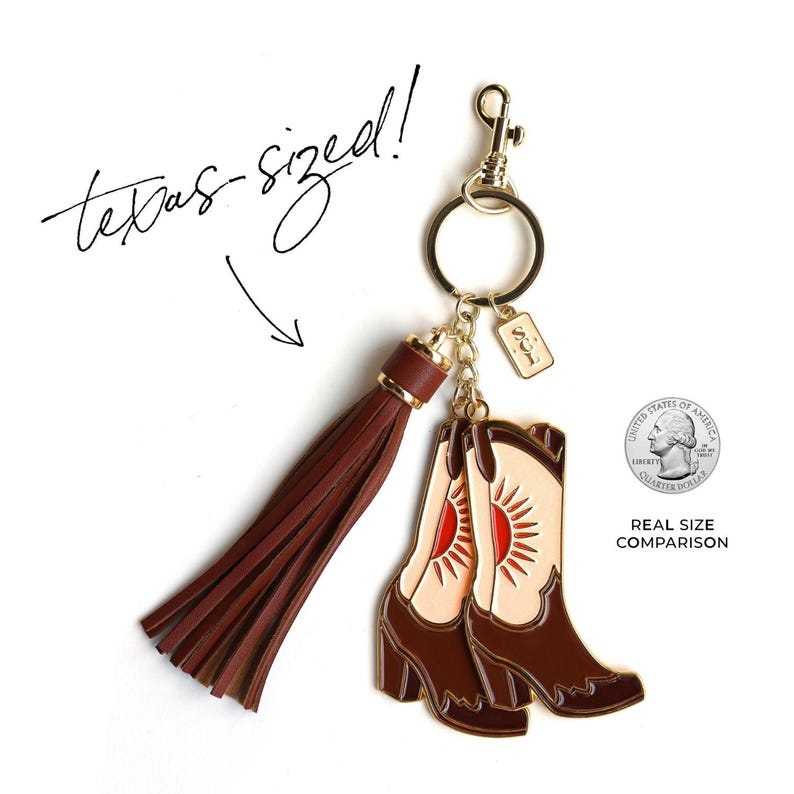 May include: A gold-tone keychain featuring a pair of brown cowboy boots with a red sun design. The keychain also includes a brown tassel. The text "texas-sized!" is written in black cursive above the keychain. A US quarter is shown for size comparison.